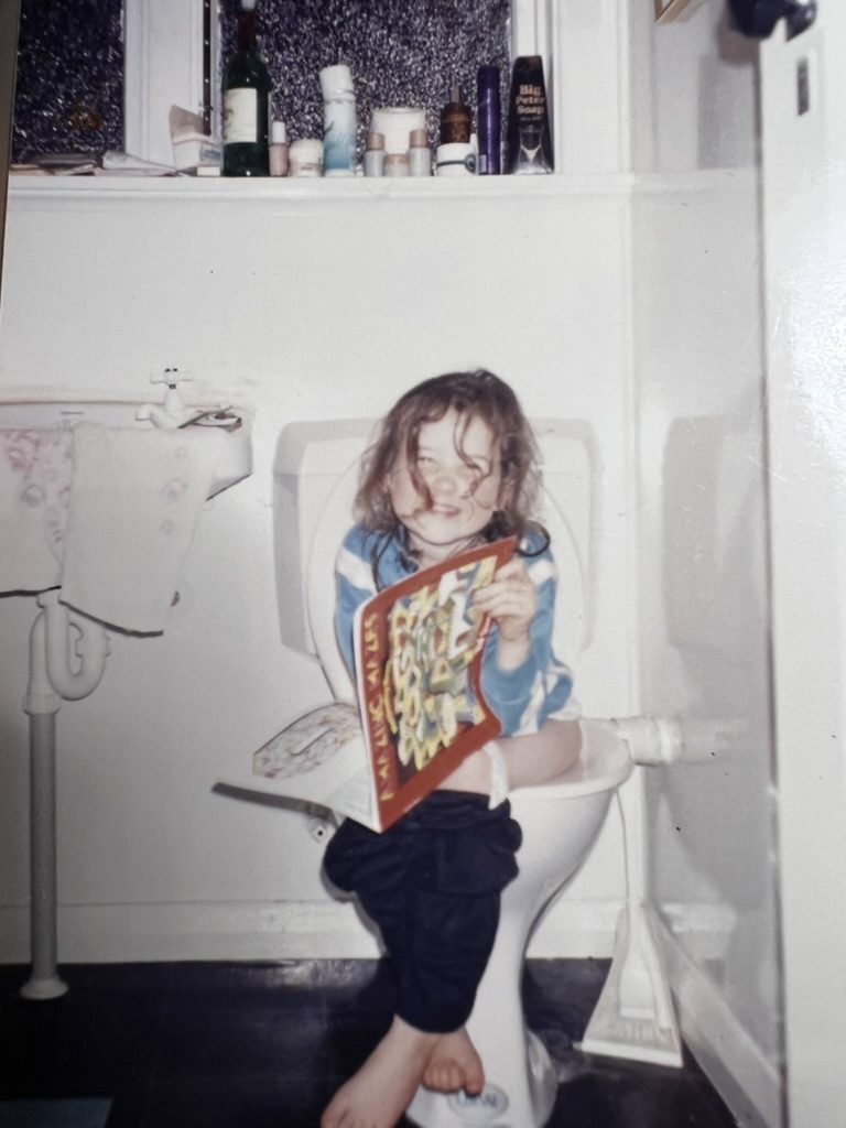 Virginia as a young child, laughing and holding an activity book.